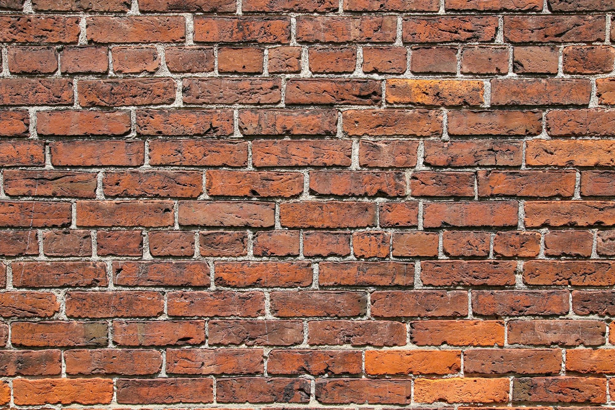 Red brick wall laid in running bond with light-colored mortar joints filled out to the brick faces